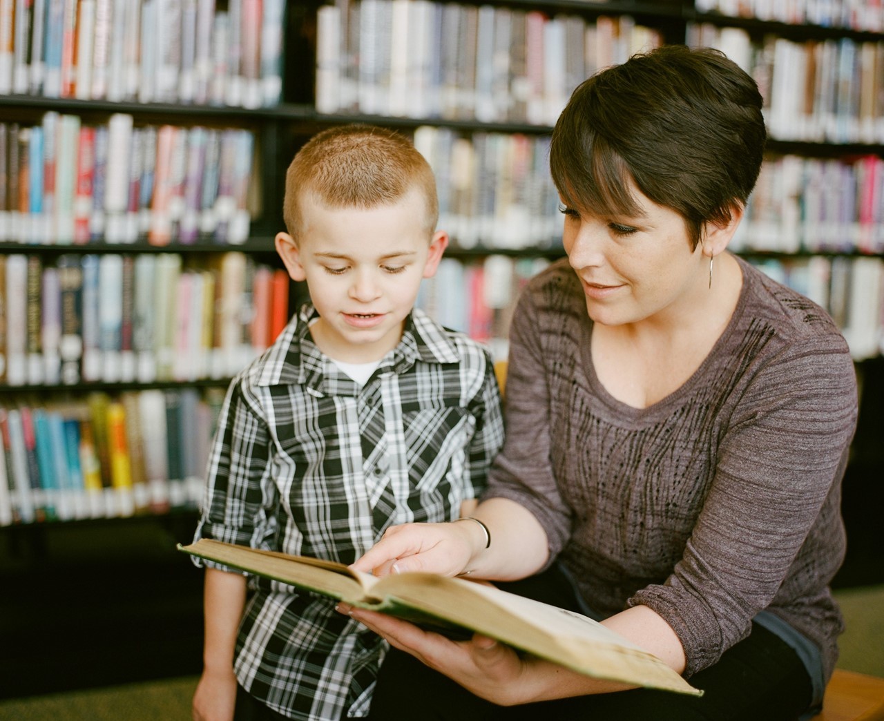 Parent and pre-schooler reading a book in a library